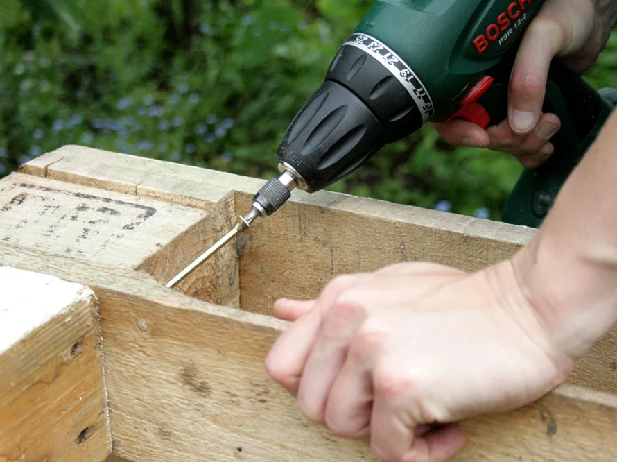 Person verschraubt Holzbalken mit Akkuschrauber