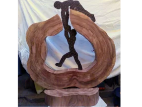 Holzskulptur: Zwei Personen helfen sich gegenseitig