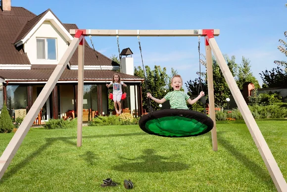 Zwei Kinder schaukeln im Garten.