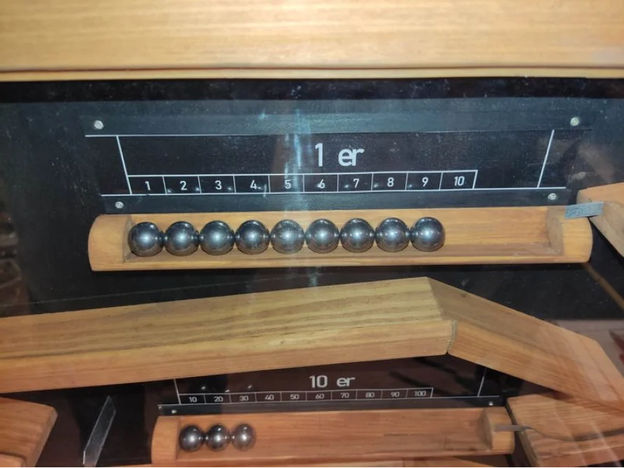 Ein Zählrahmen aus Holz mit Metallkugeln.