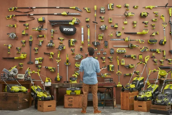 Person betrachtet Wand mit Gartengeräten