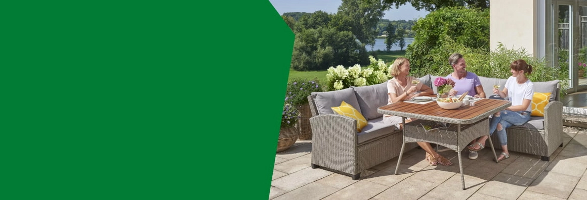 Drei Personen sitzen auf einer Loungegarnitur auf einer Terrasse.