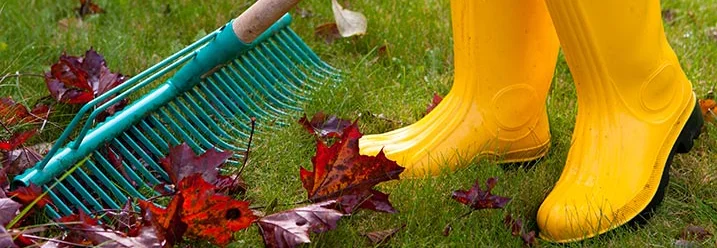 Person in Gummistiefeln mit Rechen