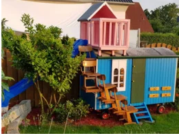 Blaues Spielhaus mit rosa Veranda und Rutsche