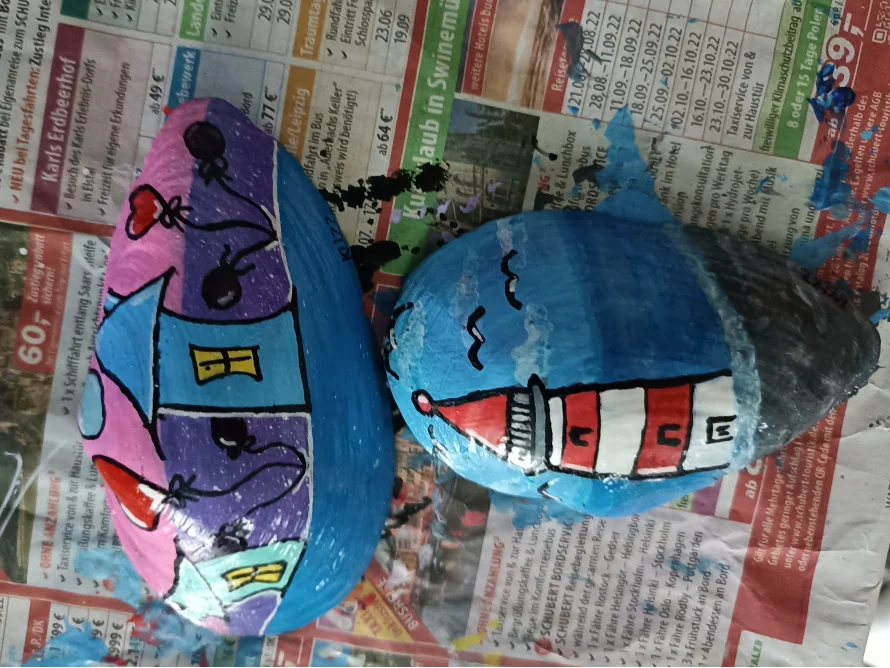 Zwei bemalte Steine: ein Haus und ein Leuchtturm