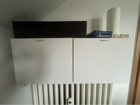 Zwei weiße Schränke über Heizung