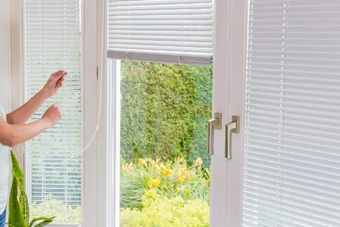 Person justiert Jalousie an Terrassentür