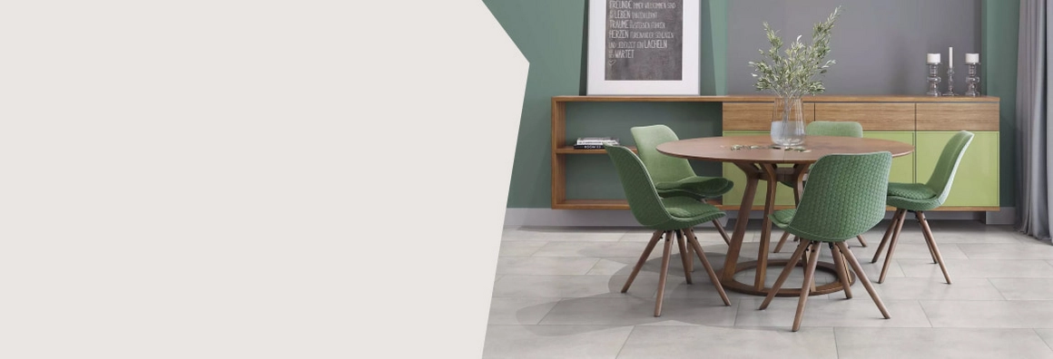 Grüne Stühle stehen um einen Tisch auf gefliestem Boden