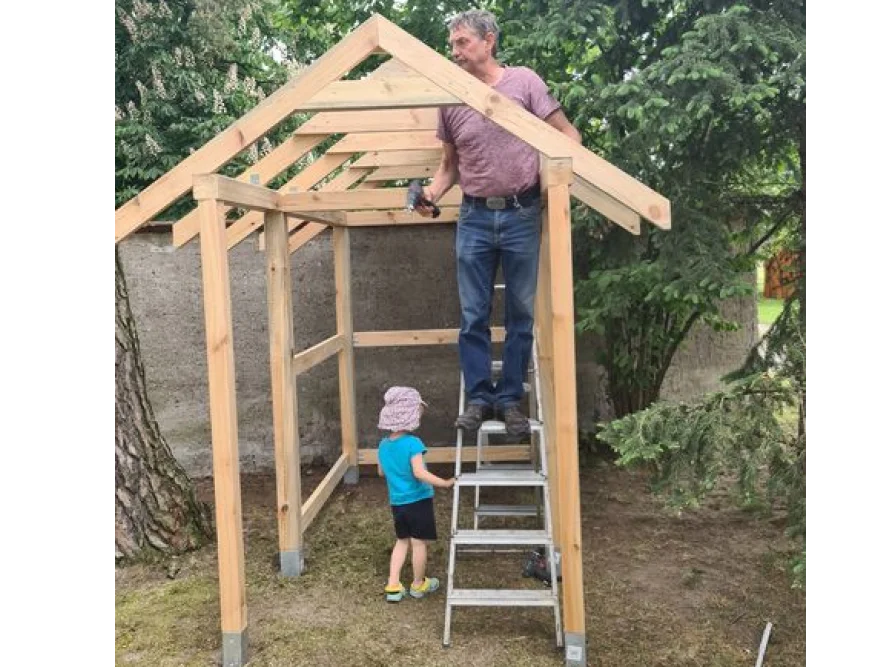 Person baut mit Akkuschrauber ein Gartenhaus