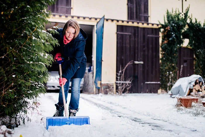 Person räumt Schnee mit Schneeschieber