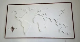 Eine weiße, dreidimensionale Weltkarte in einem Holzrahmen als Wanddekoration.