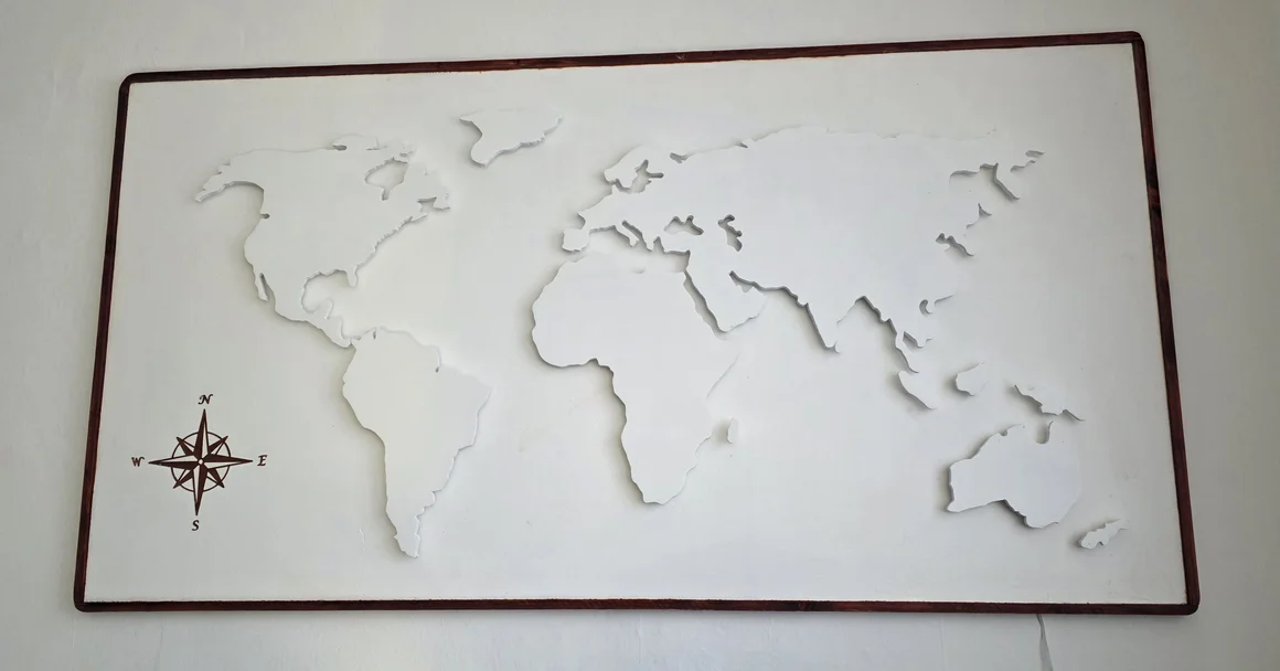 Eine weiße, dreidimensionale Weltkarte in einem Holzrahmen als Wanddekoration.
