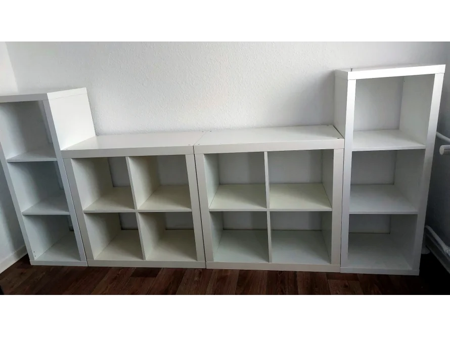 Vier weiße Würfelregale an einer Wand