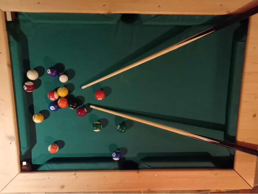 Billardtisch mit Kugeln und zwei Queues