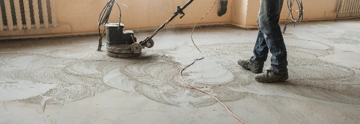 Person glättet Boden mit Schleifmaschine