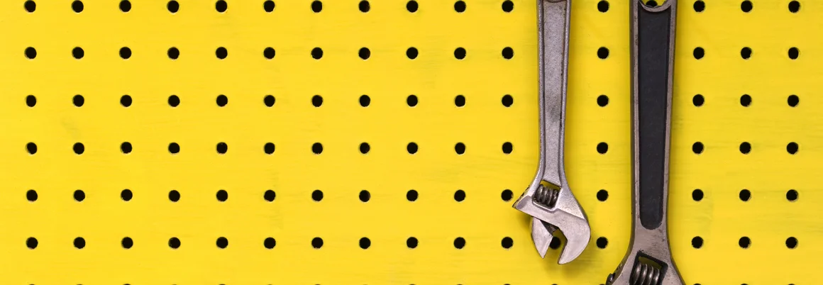 Zwei Schraubenschlüssel an gelber Lochwand