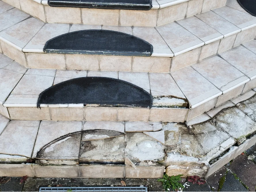 Beschädigte geflieste Außentreppe mit Antirutschmatten.