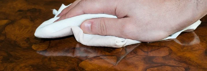 Hand poliert eine Holzoberfläche mit einem Tuch