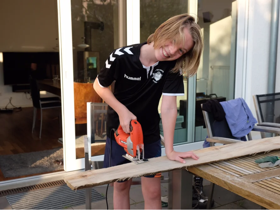 Person sägt Holzbrett mit Stichsäge