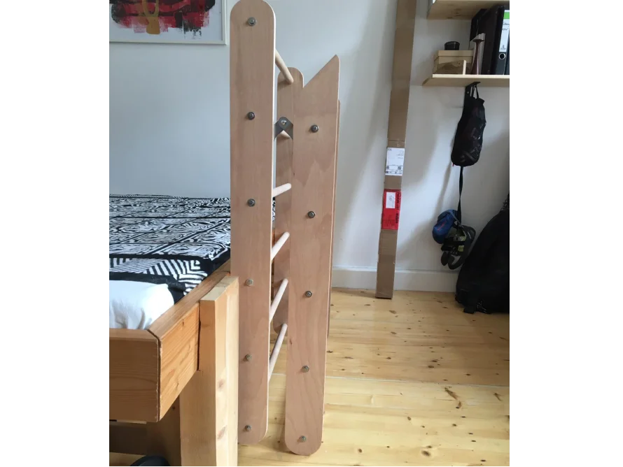Eine Holzleiter für ein Hochbett steht auf einem Holzboden.