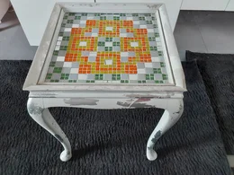 Abgenutzter weißer Tisch mit einer Mosaikplatte.