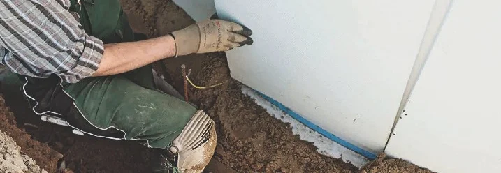 Person beim Anbringen von Dämmung an Hauswand