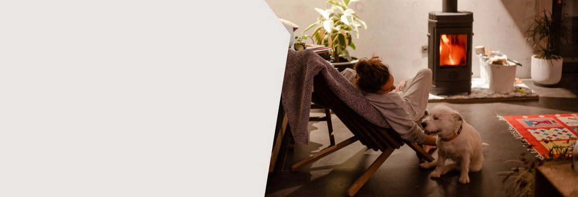 Frau mit Hund vor brennendem Kamin