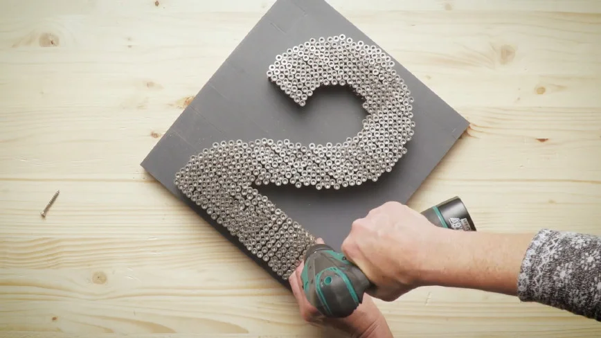 Person befestigt Schrauben an Holzplatte mit Akkuschrauber