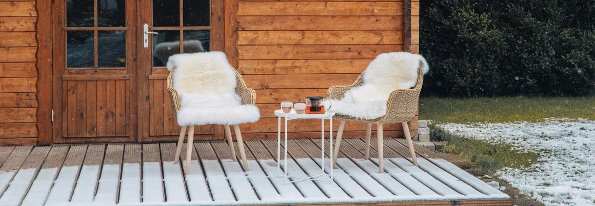 Zwei Stühle und ein Tisch auf einer Terrasse im Schnee.