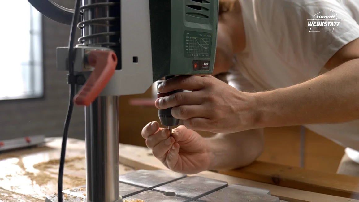 Person setzt Bohrer in Ständerbohrmaschine ein