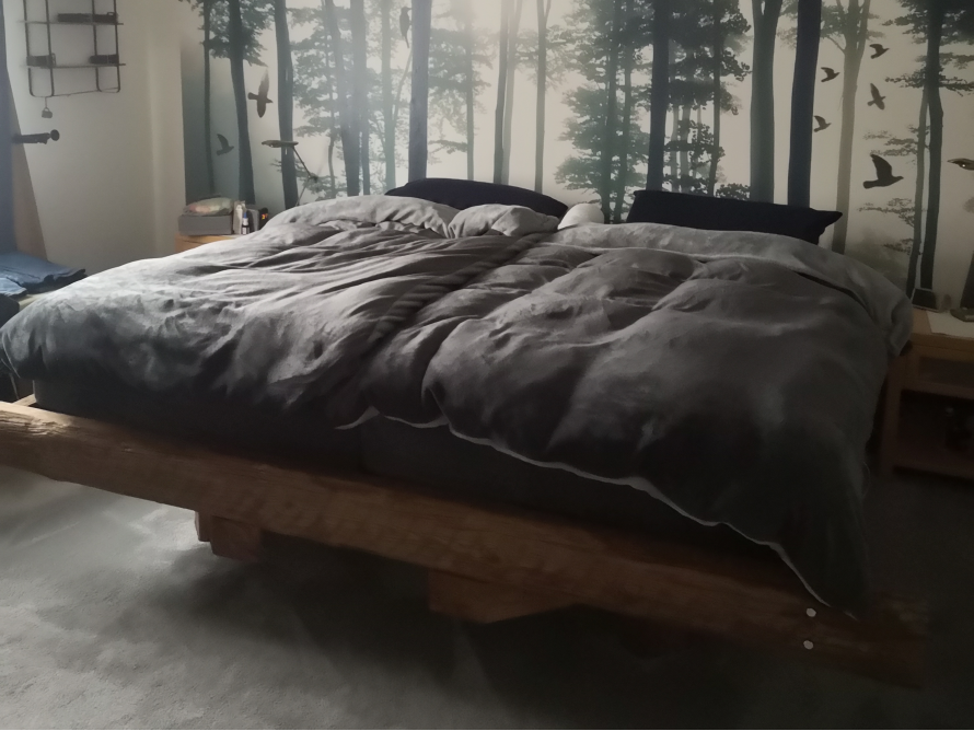 Bett mit Holzrahmen und Wandbild mit Waldmotiv