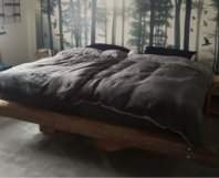 Bett mit Holzrahmen und Wandbild mit Waldmotiv