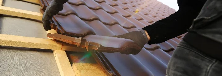Person deckt Dach mit Ziegeln.