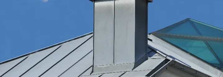 Metallkamin auf Hausdach mit Rauch