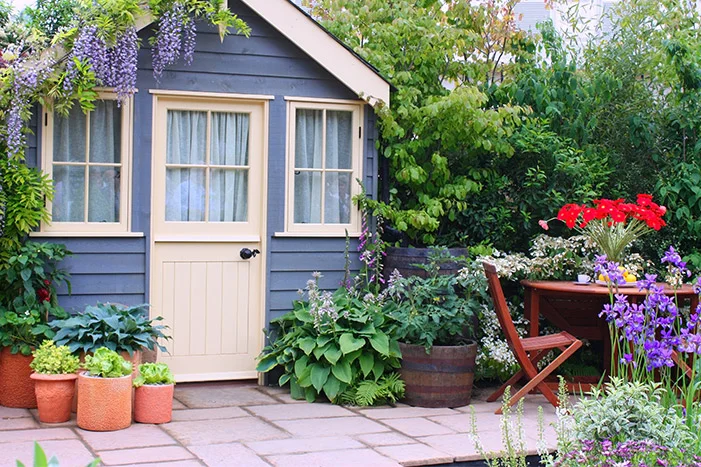 Blaues Gartenhaus mit Terasse und Gartenmöbeln