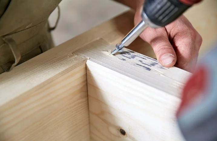 Person verschraubt Holzbalken
