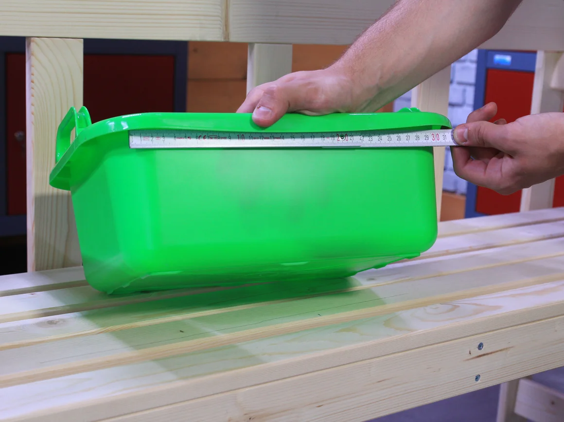 Eine Person misst eine grüne Plastikwanne mit einem Zollstock aus.