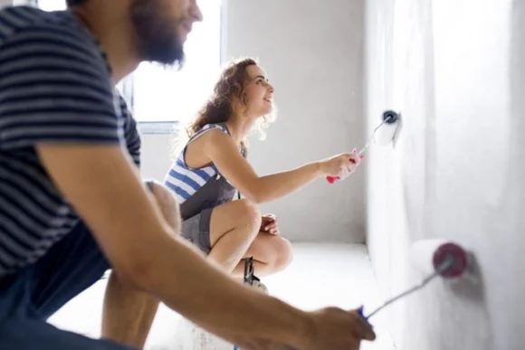 Zwei Personen streichen eine Wand weiß.