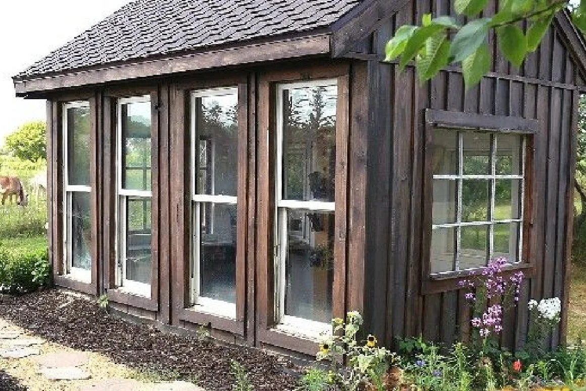 Kleines Gartenhaus aus Holz mit vielen Fenstern