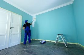 Maler streicht hellblaues Zimmer weiß an