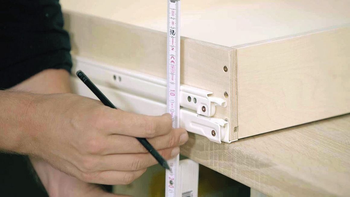 Der Handwerker misst die Höhe der Auszüge der Schublade aus.