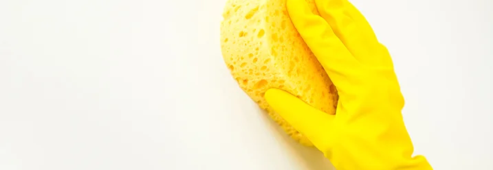 Hand in gelbem Gummihandschuh mit Schwamm
