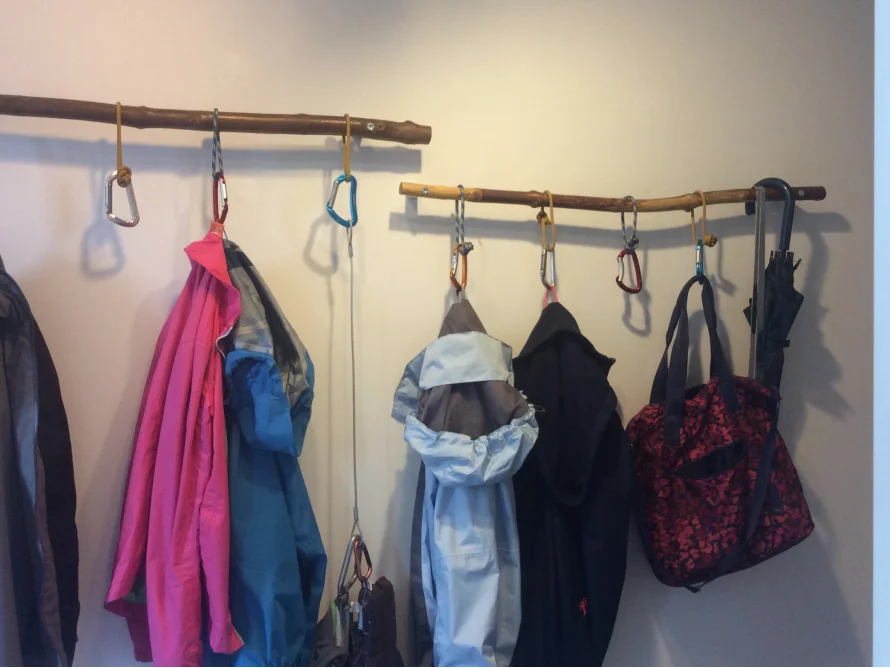 Garderobe mit Kleiderbügeln aus Ästen und Karabinerhaken