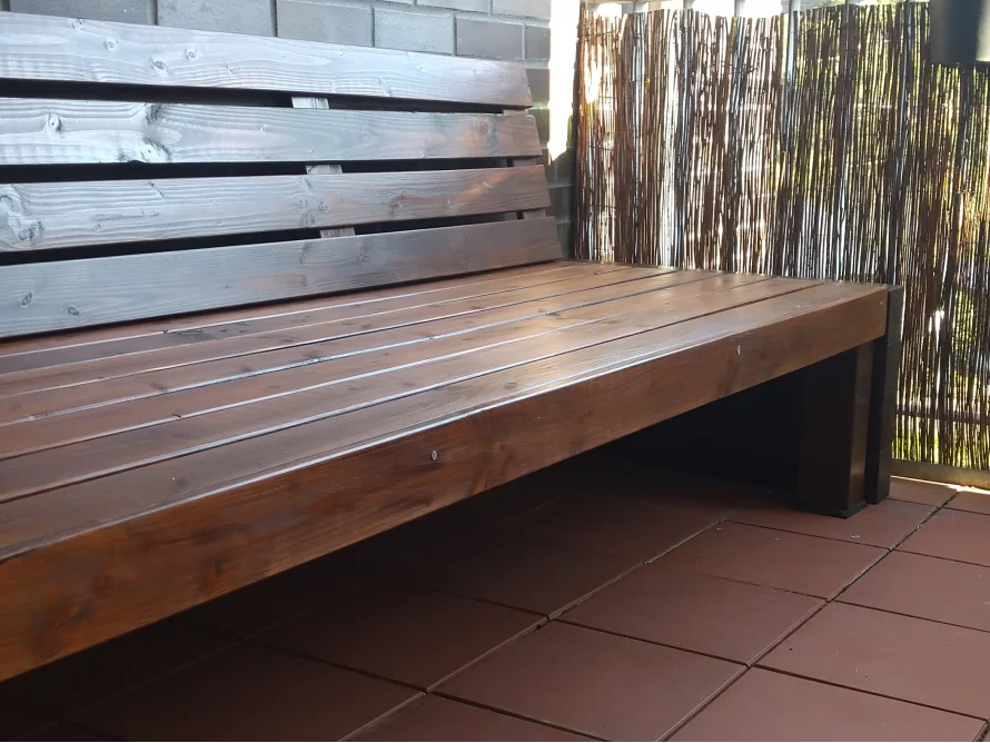 Dunkel geölte Holzbank auf einem Balkon