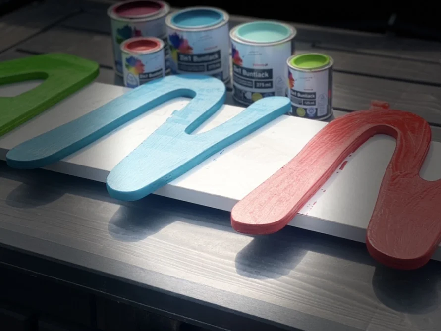 Bemalte Holzbuchstaben und Farbtöpfe