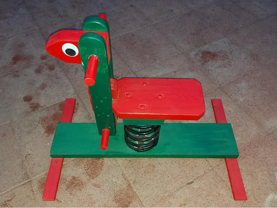 Ein rotes und grünes Spielzeugpferd mit Sprungfeder