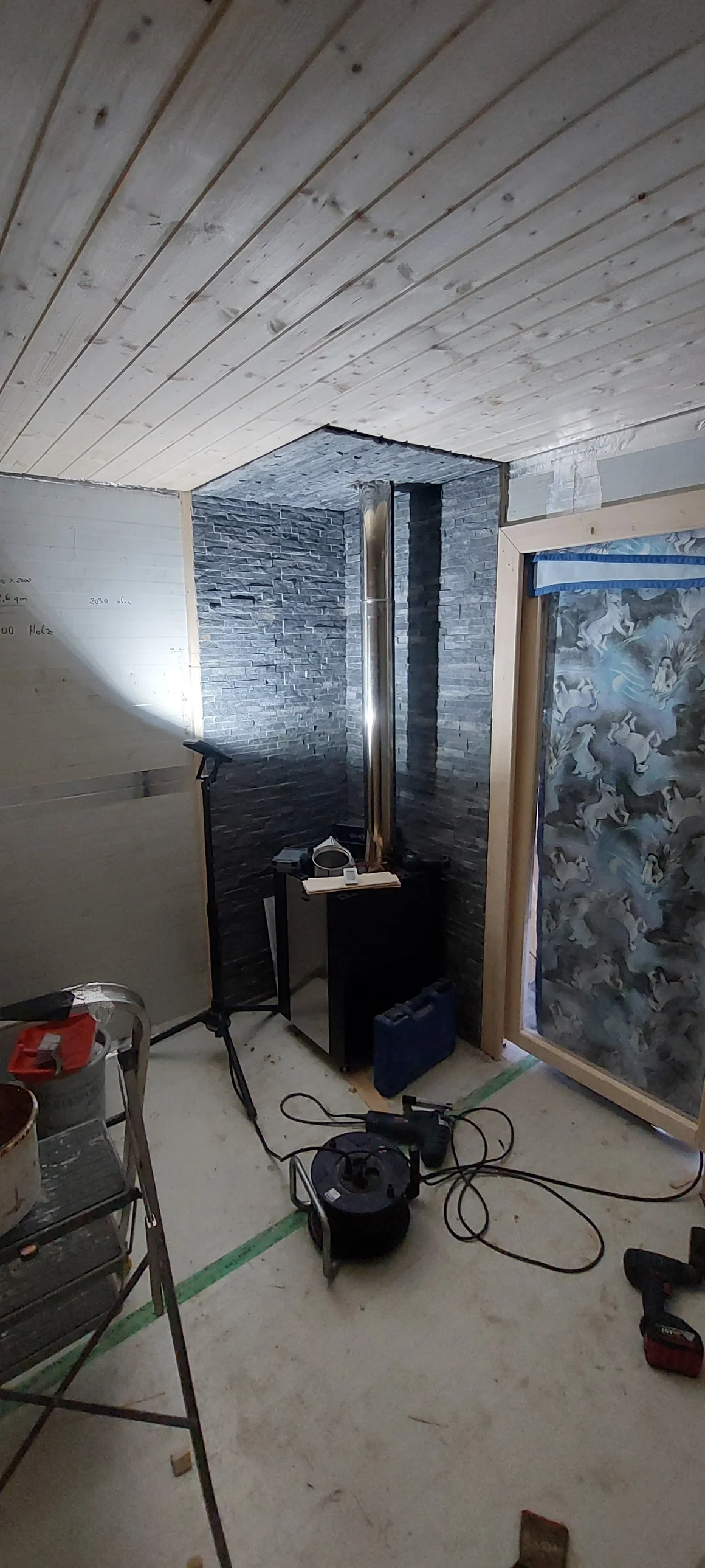 Einbau eines Ofens vor einer Steinwand in einem holzverkleideten Raum.