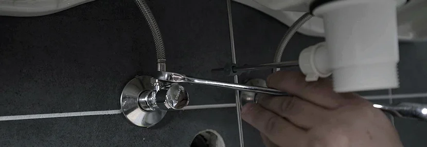 Person montiert einen Wasserhahn mit Schraubenschlüssel.