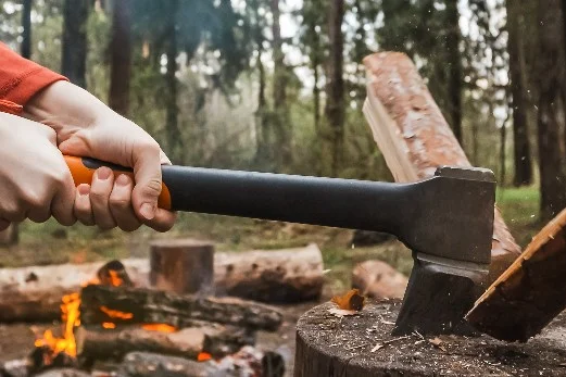 Person hackt Holz mit Axt