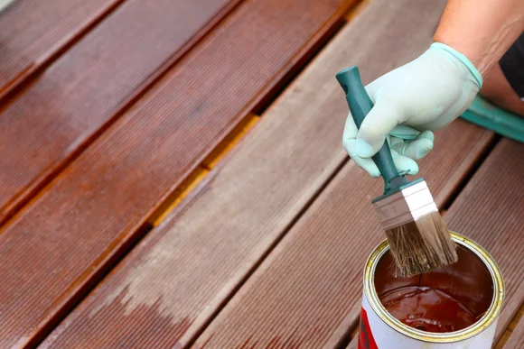 Person streicht Holzdielen mit Pinsel